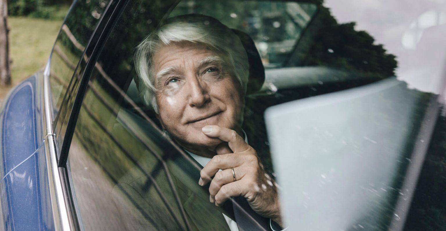 Senior citizen passenger enjoying a comfortable private car ride or chauffeur driving service.